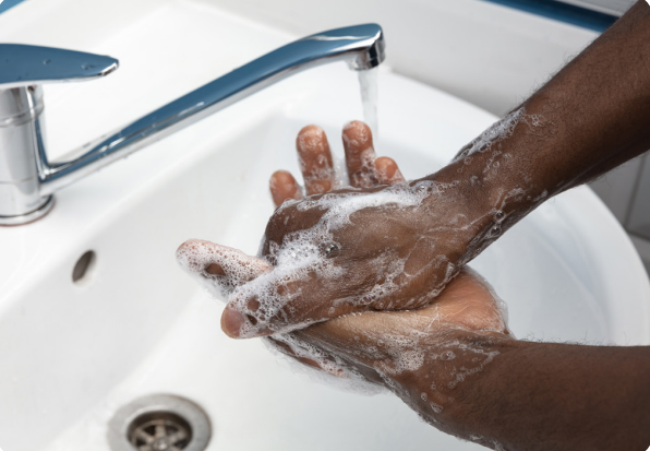 Hands lathering soap underneath a faucet of running water